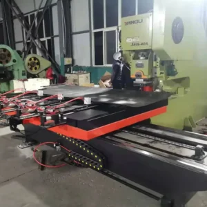 Industrial workshop with a large green hydraulic press and a black-and-orange worktable plugged into red cables