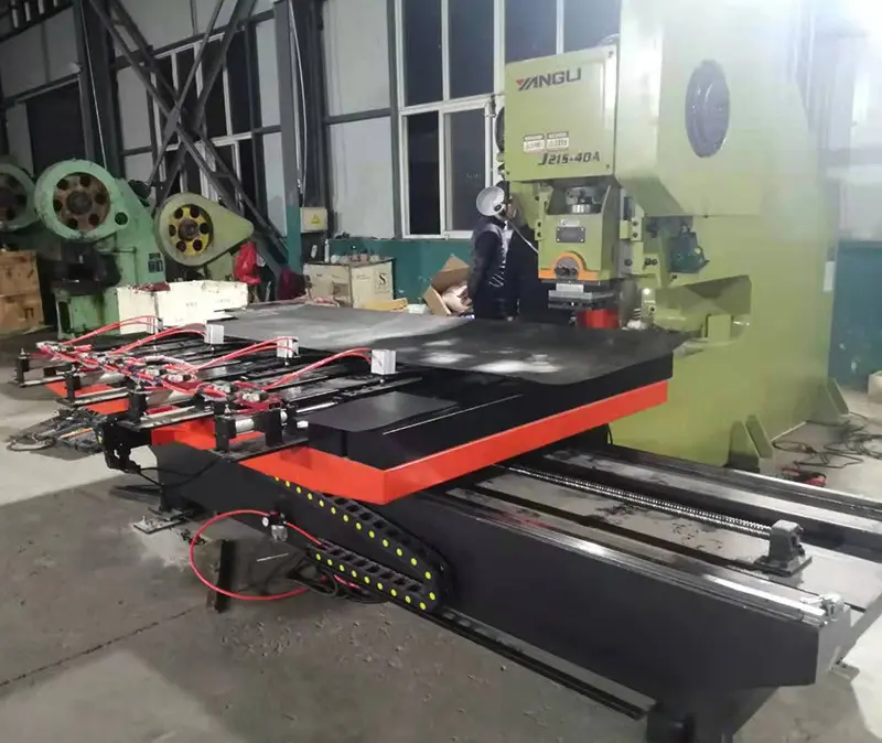 Industrial workshop with a large green hydraulic press and a black-and-orange worktable plugged into red cables